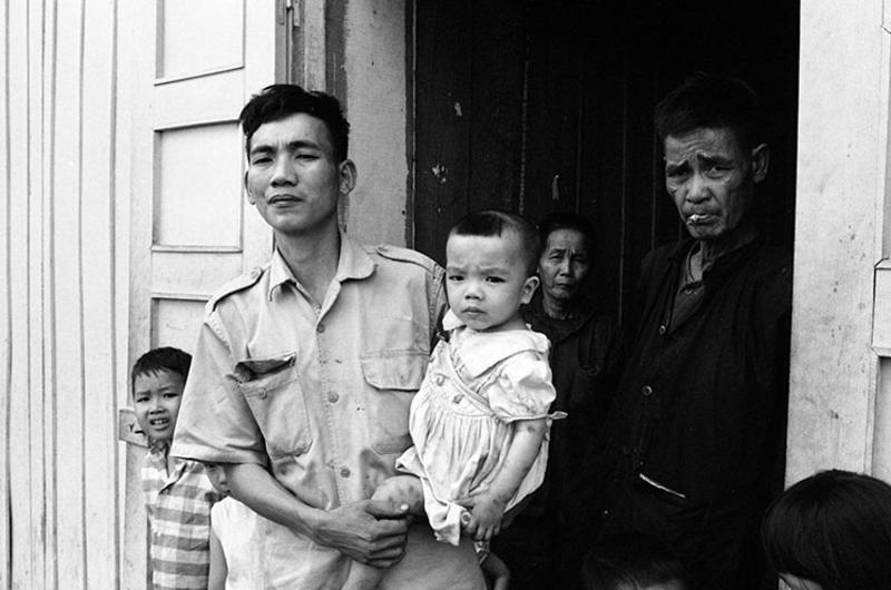 A Vietnamese family with two children stands in the doorway, somewhere in South Vietnam. Photographer did not provide any caption information for this photo.