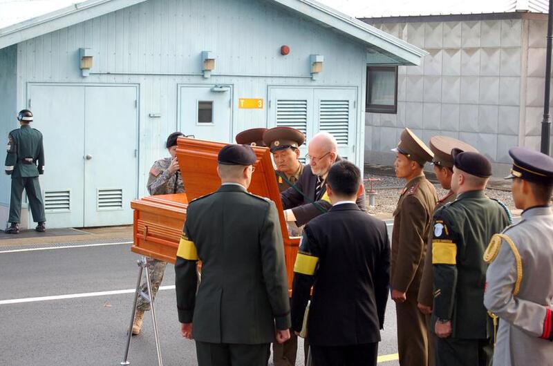 A light brown coffin is inspected by officials.
