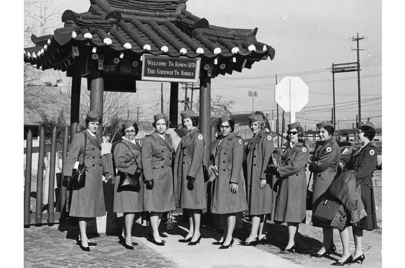 A black and white photo of women in trench coats.
