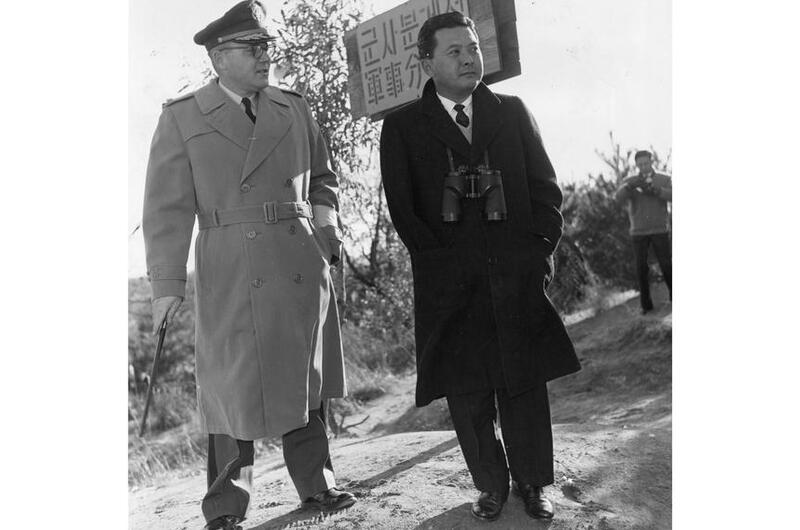A black and white photo of two men in trench coats.
