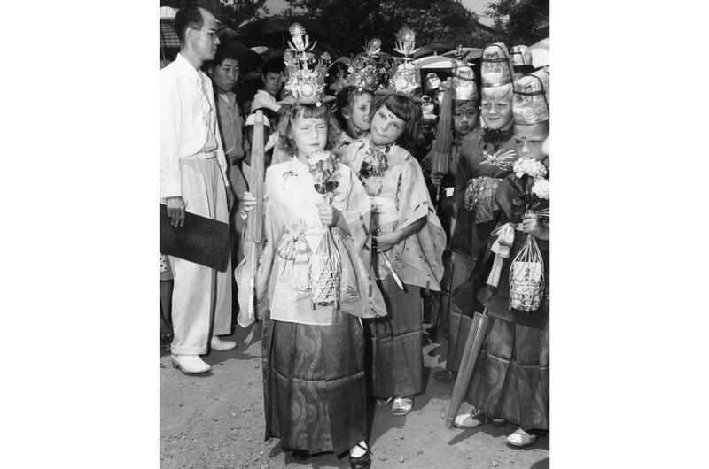 A vertical, black and white photo of a young people wearing traditional Japanese garments.