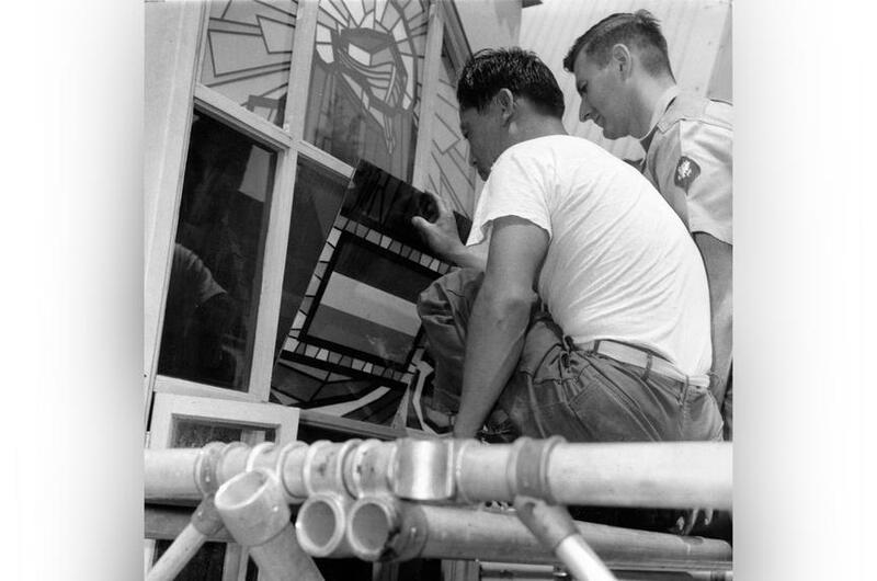 A man installs a window pane of a chapel.