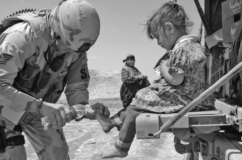 From the Stars and Stripes archives: Tech. Sgt. Jeffrey Fort, 33, of Florissant, Mo., an Air Force patrol leader, treats a local child for cuts on her feet during a recent patrol outside Ali Base in Iraq, April 2006.