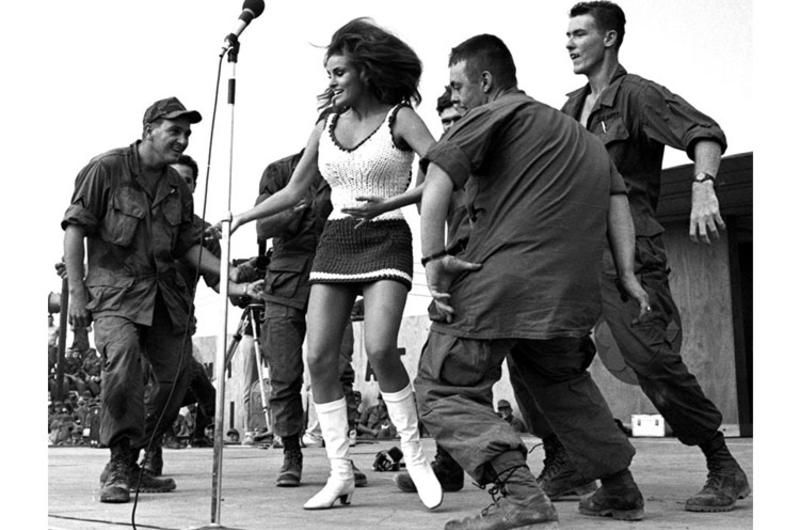 Actress Raquel Welch dances with soldiers she invited onstage during Bob Hope's USO Christmas show at the 9th Infantry Division's Bear Cat base camp.