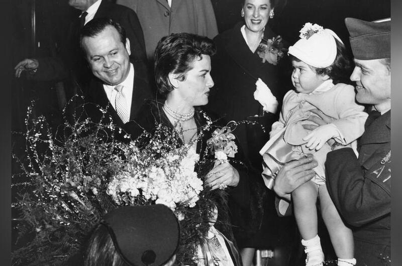 Jane Russell turns to greet a baby.
