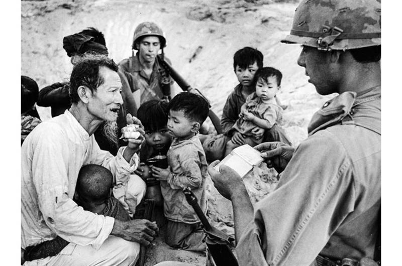 Gesturing toward his beard, a Vietnamese man tries to convince an infantryman who's checking his identity papers that he's too old to be a Viet Cong soldier.