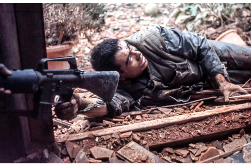 A U.S. Marine holds out his M-16 rifle to pull a wounded comrade to safety during the battle for the city of Hue.