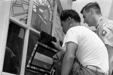 Spec. Martin H. Spielman watches as post enginner Hwang Yul An installes one of the stained glass window panes in the South Post Chapel at Yongsan Compound in Seoul, South Korea. 