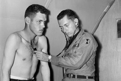 Chest checkup is given to PFC Rollie E. Fansler of the 4th Missile Command by Capt. Alan J. Serrins, medical officer of the 17th Inf. aid station. Although small, the station is one of the best-equipped military medical facilities in Korea.