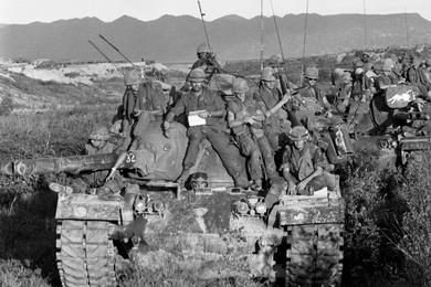 Marines of the 1st Battalion, 1st Regiment, 1st Marine Division - piled on top of tanks and Landing Vehicles Tanks (LVTs)-  move to take up position on the south side of Go Noi Island.