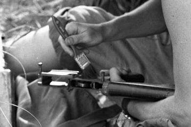 Using a paint brush a U.S. Marine cleans his rifle from sand and debris. The Marine is a member of the 1st Battalion, 1st Regiment, 1st Marine Division, taking part in Operation Pipestone Canyon.