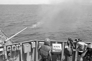 The five-inch gun on the USS Buchanan fires at targets on shore, north of Dong Hoi.
