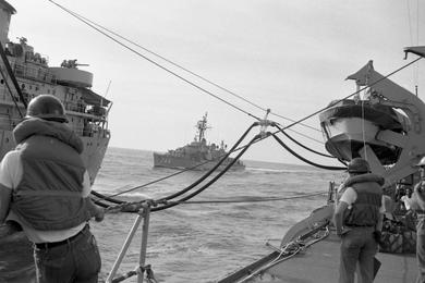 The USS Blue - an Allen M. Sumner class destroyer - can be seen floating in the background as sailors oversee the refueling operation on board the USS Buchanan destroyer by the tanker USS Tappahannock.