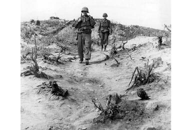 Two American soldiers cross the battered terrain surrounding Outpost Harry.