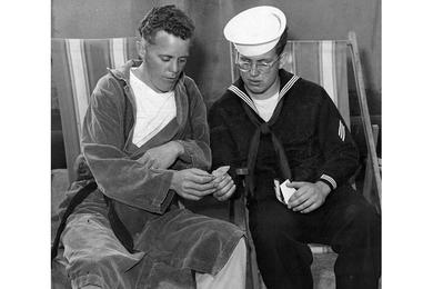 Cpl. William L. Conley, 23, Morrilton, Ark., recently released from a Communist prisoner of war camp, and brother, SM Tom, 20, of the destroyer Laws, look at Tom's pictures and clippings from home during their visit on the 8167th Army Hospital sundeck.