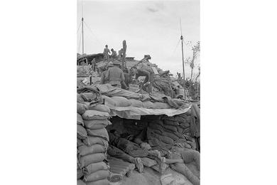 Soldiers rest in their bunker while others fill sand bags and receive daily rations.