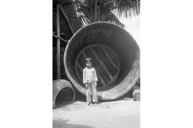 Youngster standing in an empty Nuoc Mam vat of An Thoi Nuoc Mam factory.