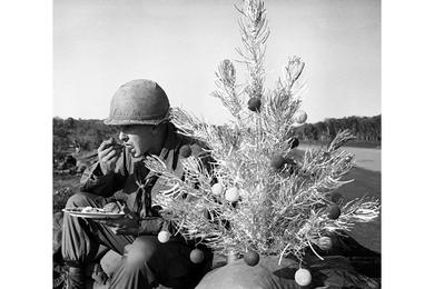 Spec. 4 Ron Brault of Kansas City, Mo., eats dinner while sitting next to a Christmas tree sent to him by his parents.