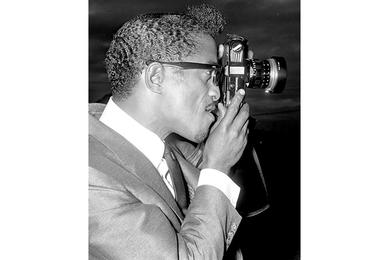While awaiting a helicopter flight to Tachikawa Air Base, where a crowd of 8,000 Air Force personnel gathered for his show, Sammy Davis Jr. tries out one of Japan's more popular products.
