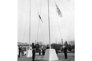 The five-ring Olympic flag and the Japanese national flag are raised at Washington Heights in Tokyo Tuesday.