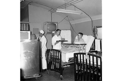 Big food wagons make the rounds of the 121st's wards as SFC John H. Jackman (right), Hq. Svc. Co., 802nd Eng. Bn., receives his supper from PFC Kermit W. Tesch, wardman