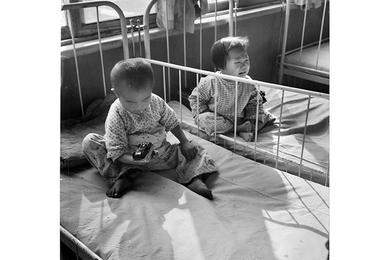 Pair of young orphans await the arrival of their noon meal.
