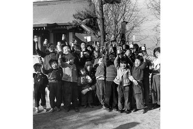 Cheers Go Up for Capt. Chavez as the orphans, holding canned soft drinks afloft, surrounded their benefactor, nearly hidden from view in the center, holding one of the smaller children from the orphanage.