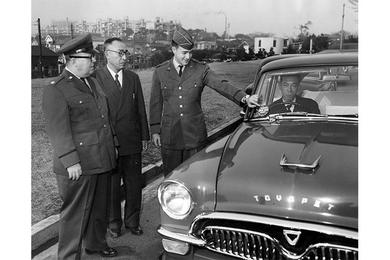Cab Service - Second Lt. Hillary Doran Jr. (center) 421st Air Police Washington Heights Det., puts a windshield sticker on the cab of Kiyoe Miyahara as a new taxi service began at Washington Heights last week.