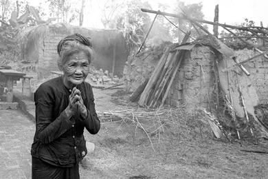 Vietnamese peasant woman watches home burn.