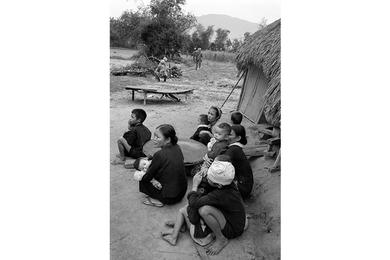Local Vietnamese look on as cavalrymen on patrol pass through their village.