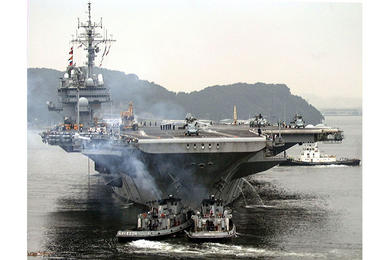 U.S. and Japanese tugs help push the USS Kitty Hawk away from the pier as it leaves for sea trials and exercises in the Philippine Sea.
