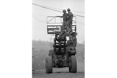 Troops work on overhanging electrical wiring at Khe Sanh Base.