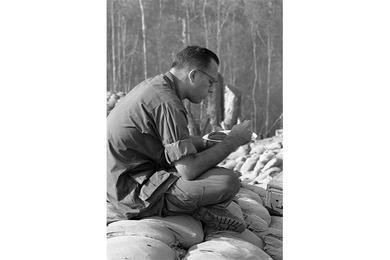 A soldier sits down on some sand bags for his meal at Fire Support Base 25.