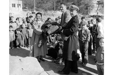 CLOTHING PRESENTATION - Mrs. On Soon Lee, director of the Pubwon Orphanage, accepts a clothing donation from Charles D. Crocker (center), U.S. Operations Mission, and Lt. Cdr. Voster F. Comstock, Naval Advisory Group, Korea.