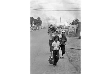 Refugees flee burning buildings near Tan Son Nhut. Viet Cong and North Vietnamese forces started shelling more than 120 provincial capitals, towns and allied military installations across South Vietnam  and battled governement and U.S. troops inside the capital Saigon, May 5th.