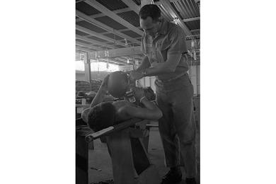 Patient whose helmet was riddled by schrapnel shows helmet to corpsman.