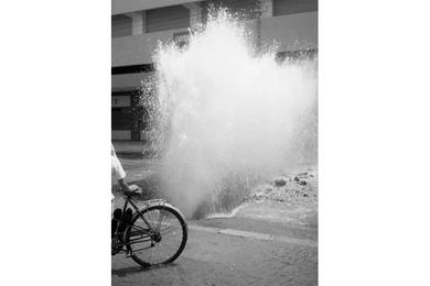 Water shoots out of a burst pipe under a road in Saigon.