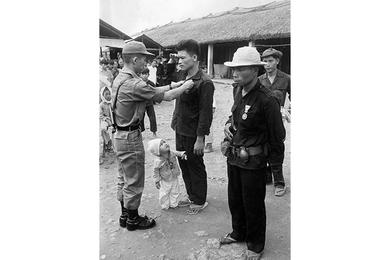 A village defender receives a medal as his son watches.