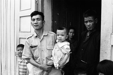 A Vietnamese family with two children stands in the doorway, somewhere in South Vietnam. Photographer did not provide any caption information for this photo.