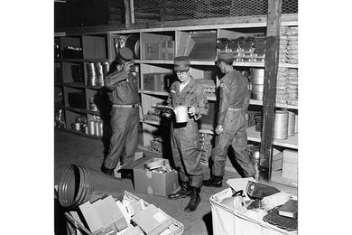 CHECKING ON STOCK in the new center, M/Sgt. William J. Ward of the 13th QM Bn. holds a coffee pot and a clip board.