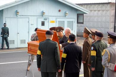 A light brown coffin is inspected by officials.