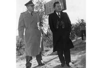 A black and white photo of two men in trench coats.