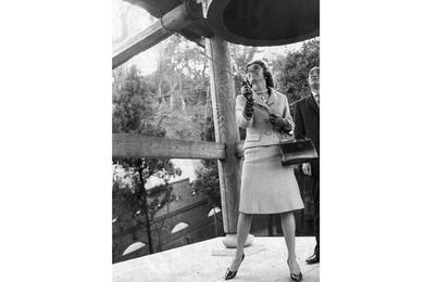 A vertical, black and white photo of a woman ringing a large bell.