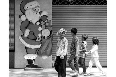 A sign bearing the image of a favorite seasonal visitor draws the attention of Vietnamese kids on a Saigon street.