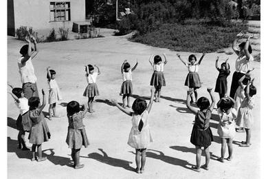 THE LITTLE ORPHAN are led in singing by Kyung Sook Ko, left, U.S. Operations Mission program, and Young Sook Kim, of the orphanage's staff.