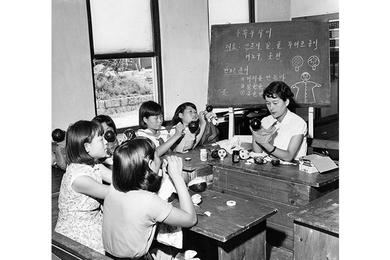 CHILDREN CAREFULLY PAINT the feature on puppets in one of the orphanage's classroom.