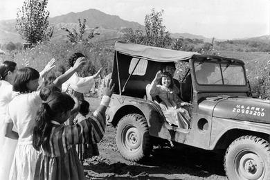 Happy orphan In Suk Han, 7, waves to her friends at the Hea Sung Orphanage as she leaves with Miss Elizabeth Lewis and an unidentified driver for a weekend in Seoul.