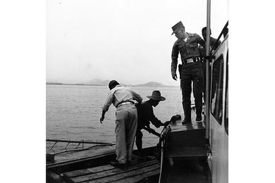 Patrol boat comes alongside small Korean boat in Inchon harbor and warns boatman to move his craft away from the ship unloading area.