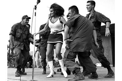 Actress Raquel Welch dances with soldiers she invited onstage during Bob Hope's USO Christmas show at the 9th Infantry Division's Bear Cat base camp.