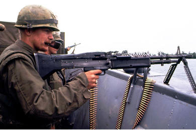 A machine gunner keeps a close eye out for enemy activity on the shoreline as U.S. Marines cross the Perfume River for an assault on the ancient imperial capital of Hue during the Tet Offensive.